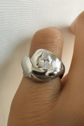 Silver ring with a zirconia on a finger against a white background