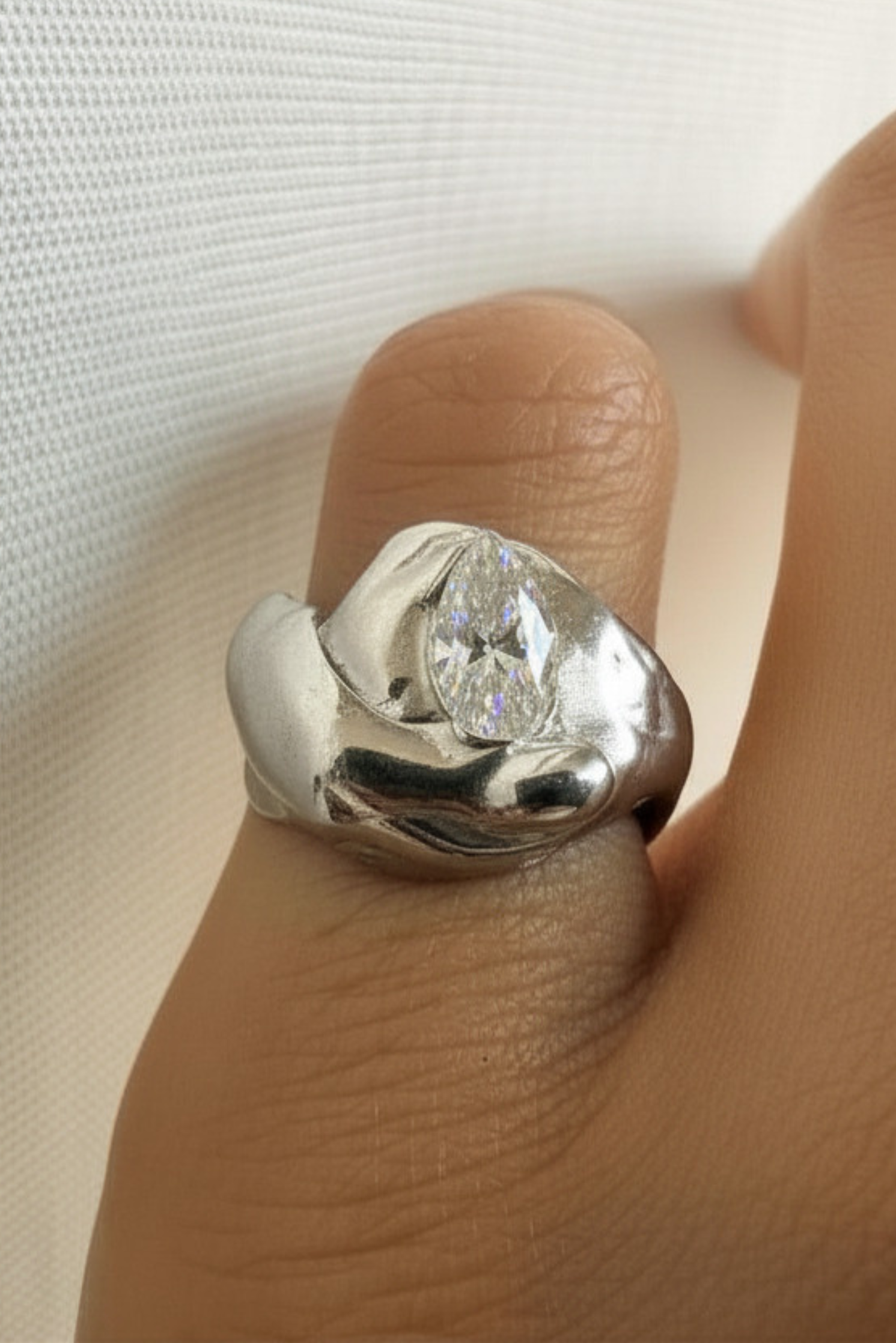 Silver ring with a zirconia on a finger against a white background