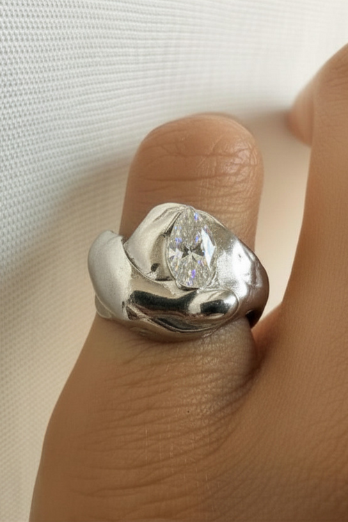 Silver ring with a zirconia on a finger against a white background